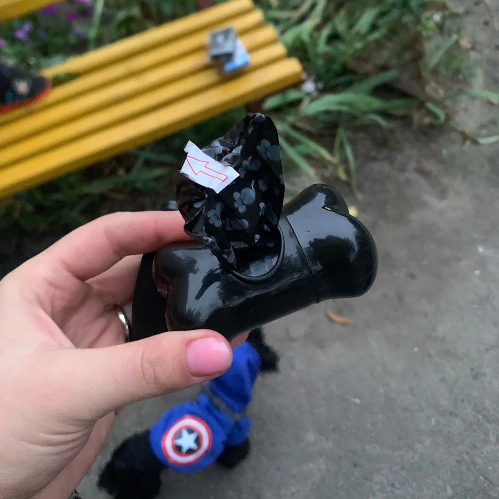 Person holding black dog poop bag dispenser during walk