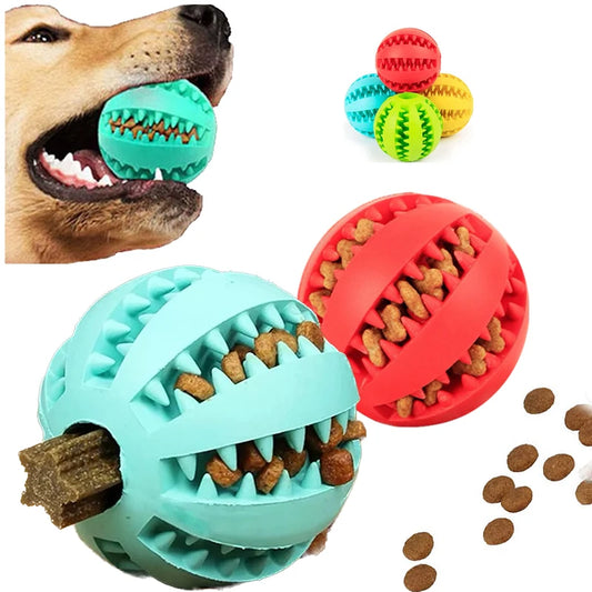 A light blue rubber dental dog ball filled with treats next to a red ball with kibble spill details and a dog chewing on a toy