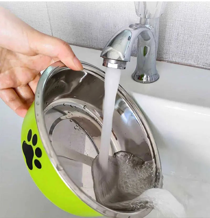Washing a green non-slip stainless steel dog bowl under a running kitchen water faucet