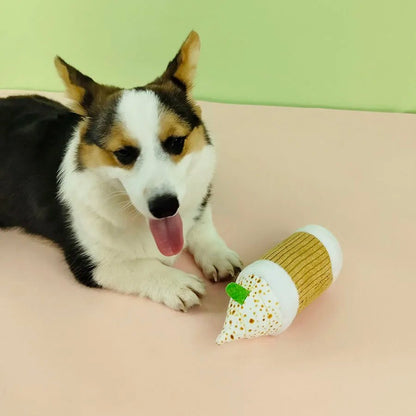 An adorable Corgi dog lying down on a mat playing with the Star Pups plush coffee cup toy