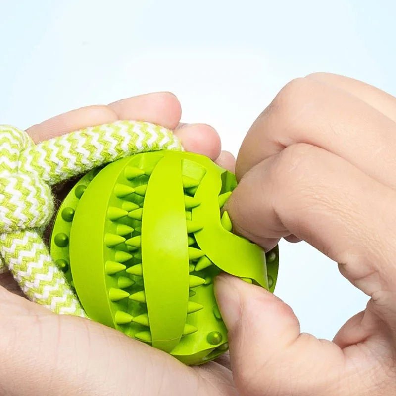 Two hands pressing down on a bright green flexible rubber ball section to demonstrate its elastic dental texture and durability