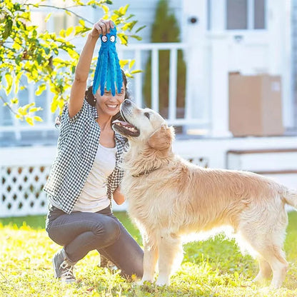 A woman playing fetch outdoors with a happy golden retriever dog using a blue octopus toy