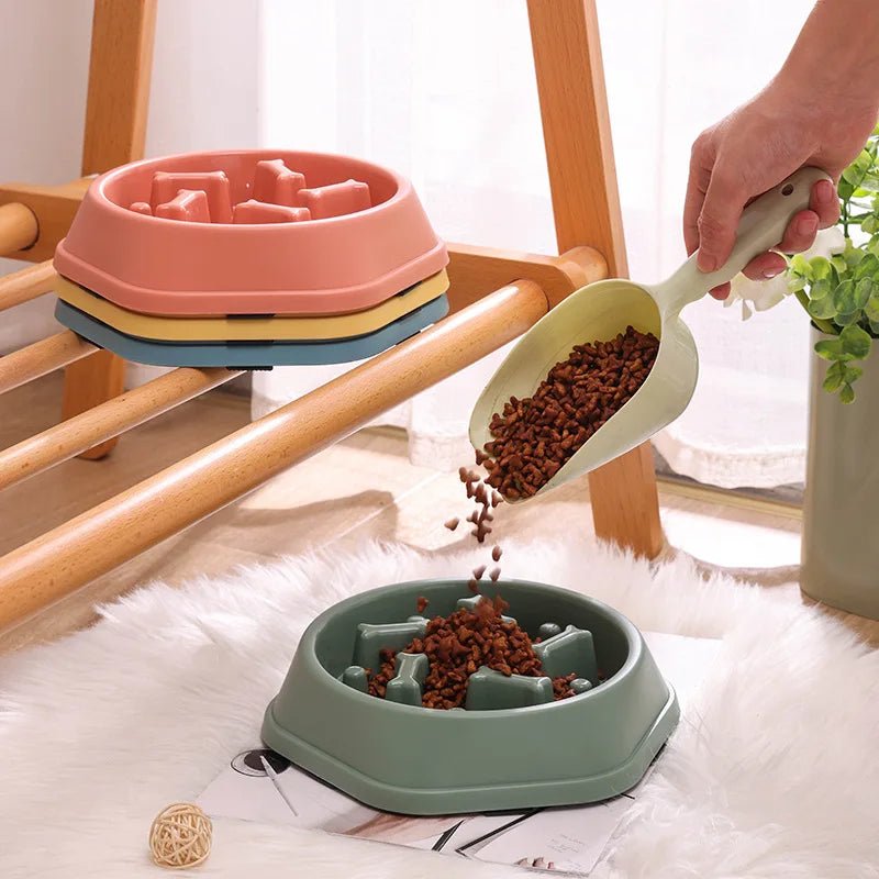 Pouring dry dog food from a scoop into a green anti-choke slow feeder maze bowl