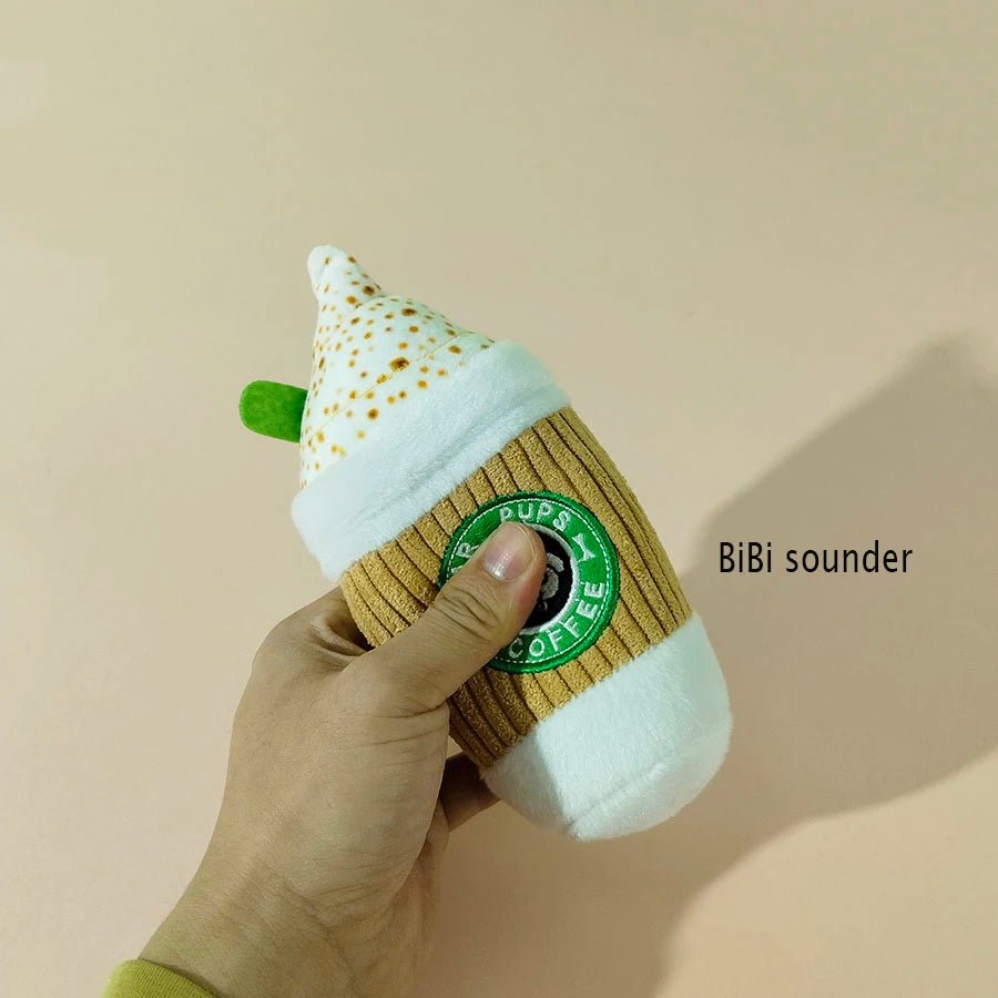 A hand squeezing the plush coffee cup toy to demonstrate the internal interactive sounder
